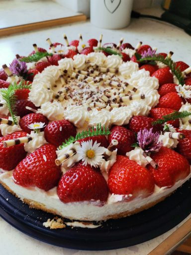 Torte mit Erdbeeren und Blumen ausgarniert