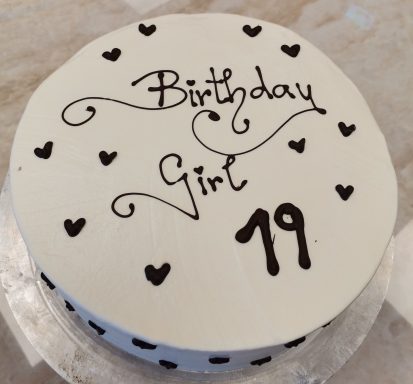 weiße Torte mit schwarzer Schrift und kleinen Herzen