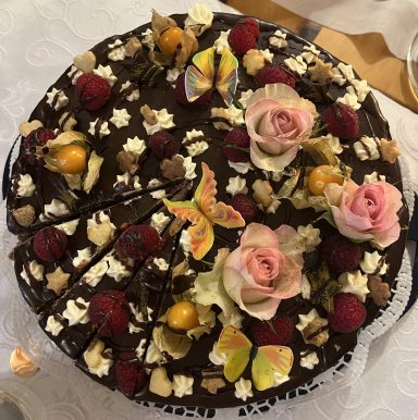 Schokotorte mit Blumen, Früchten und Esspapierschmetterlingen dekoriert